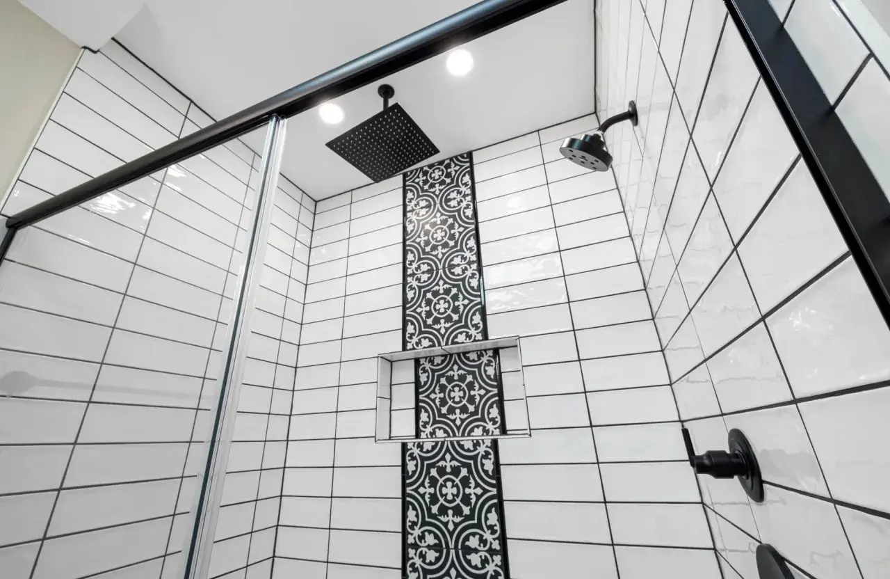 Modern shower with white subway tiles and black grout, featuring a decorative black tile accent and black fixtures.