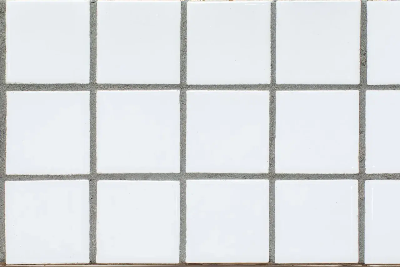 A grid of small, white square tiles with gray grout filling the spaces between them. This grout is what holds the tiles together and prevents water from seeping through.