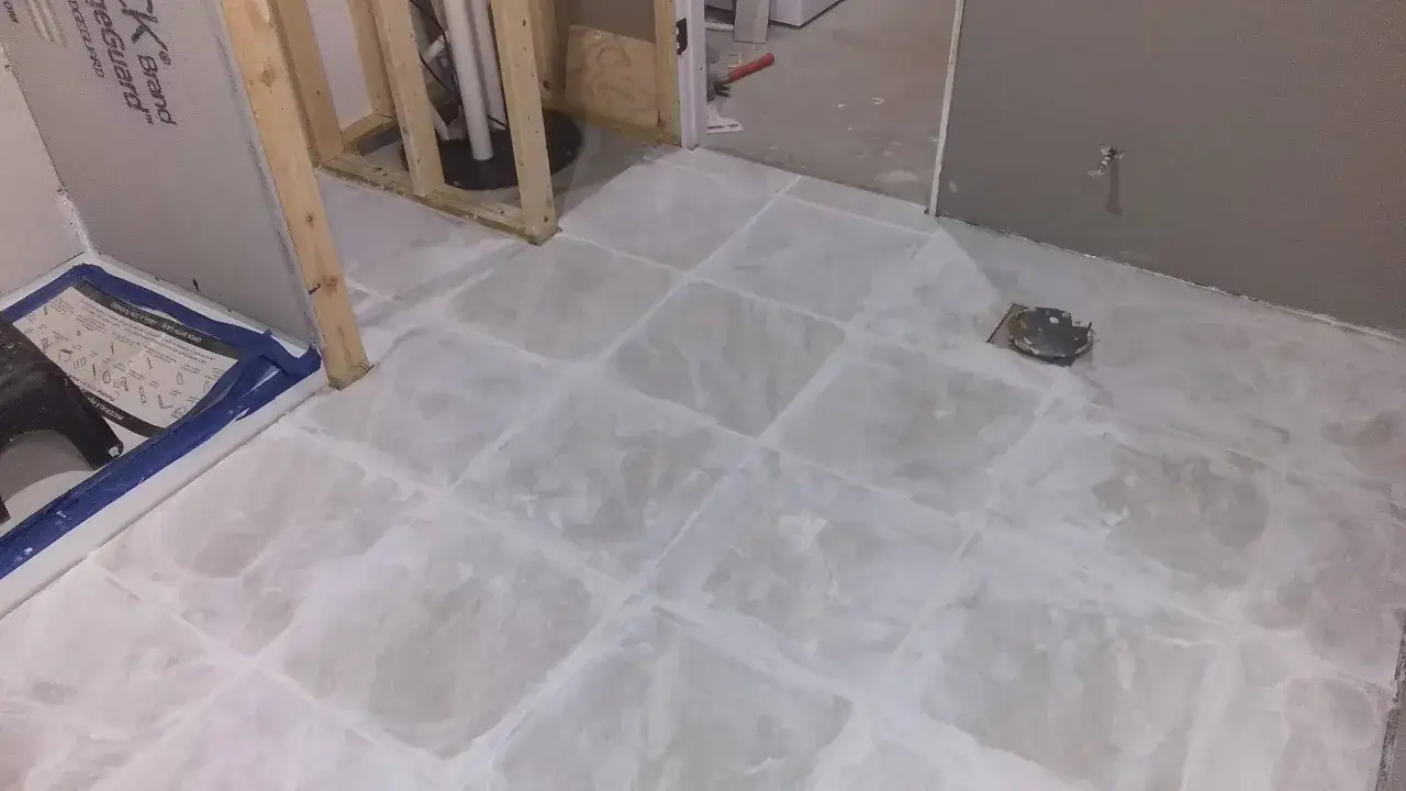 A tiled floor under construction, with a shower base on the left. The grout lines are visible, hinting at the process of how to remove grout from tile.