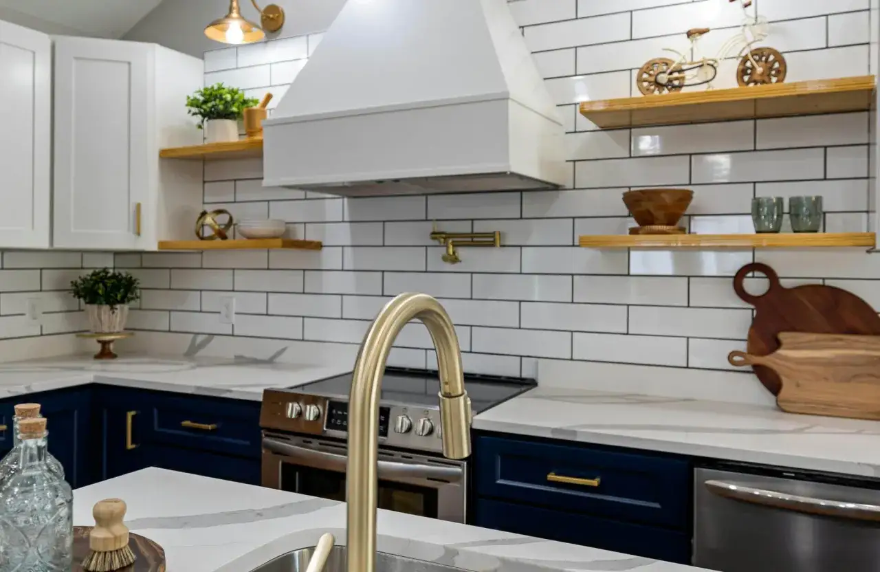 A modern kitchen features white subway tile with dark grout, navy blue cabinets, and a gold faucet.