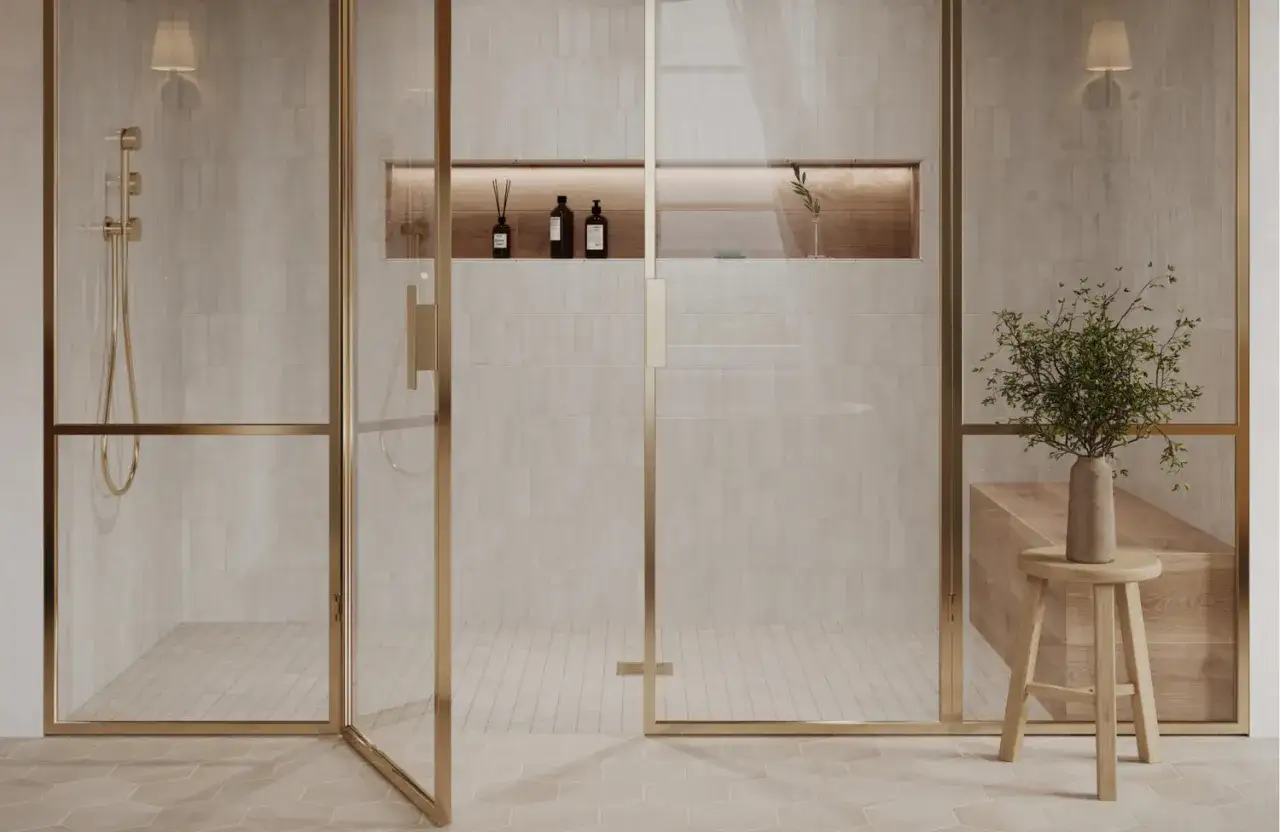 A modern bathroom with a gold-framed glass shower. The textured tile walls and hexagonal floor tiles offer a high dcof tile rating for safety.
