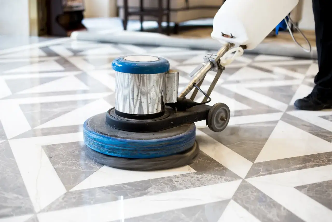 A floor buffer is polishing a geometric marble tile floor, restoring its shine.