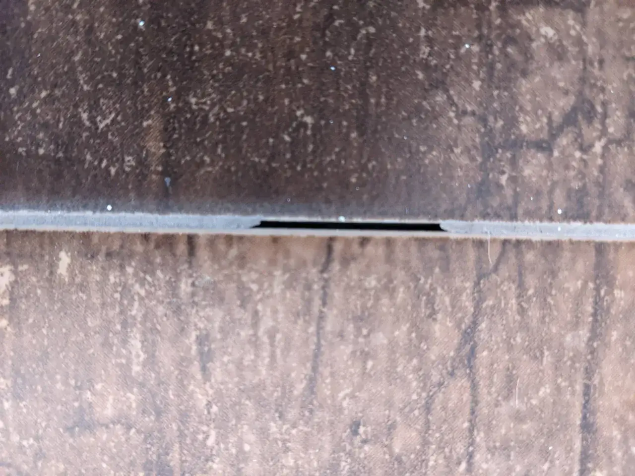 Close-up of textured brown floor tiles with a thin grout line. Wondering how often should you regrout floor tiles?