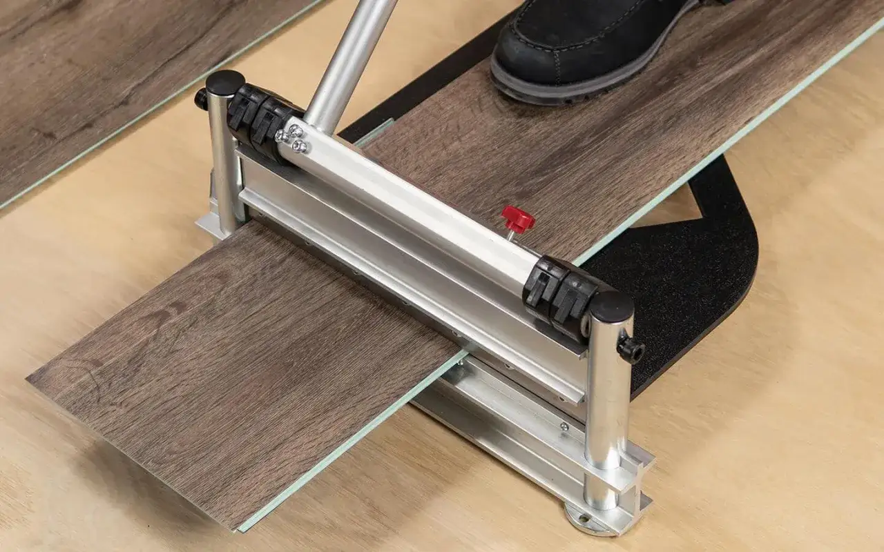 Using a cutter to score and snap a vinyl plank, a key step in how to replace vinyl plank flooring.