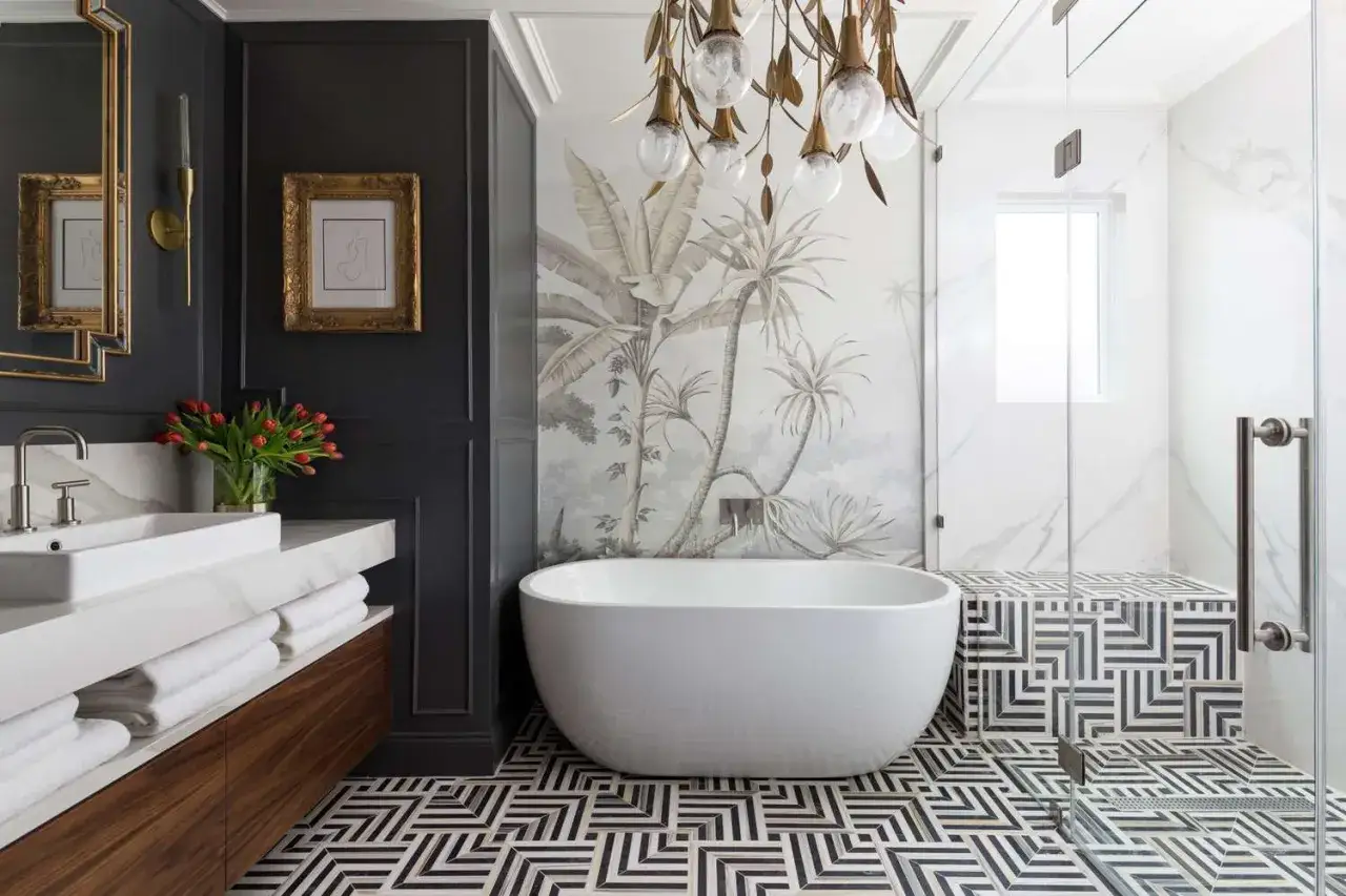 Bold geometric floor and shower tile combinations create a striking contrast with the tropical mural and freestanding tub in this modern bathroom.