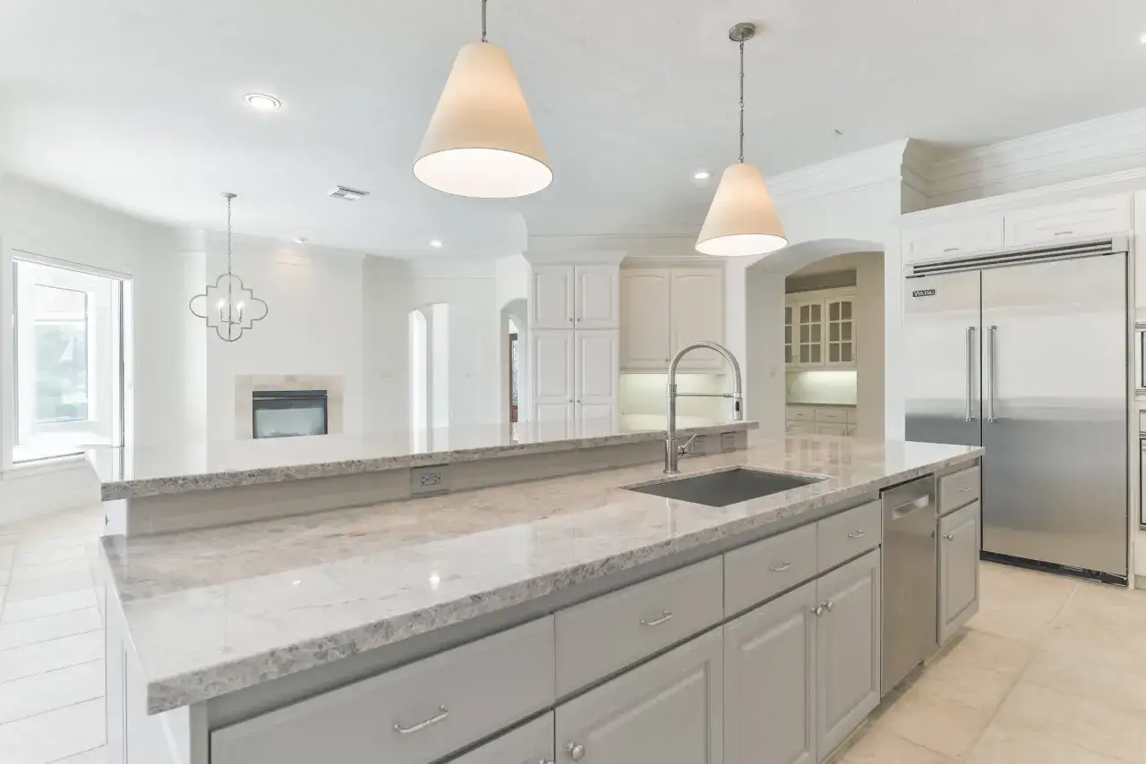 A modern kitchen with a large island, granite countertops, and a tile backsplash. This image helps visualize the cost to install tile backsplash in a high-end kitchen.