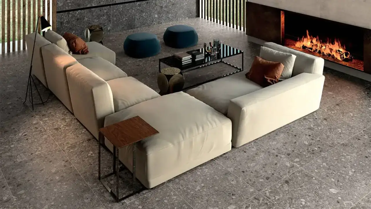 A modern living room with a large sectional sofa, fireplace, and coffee table, all set on a beautiful bella terrazzo floor.