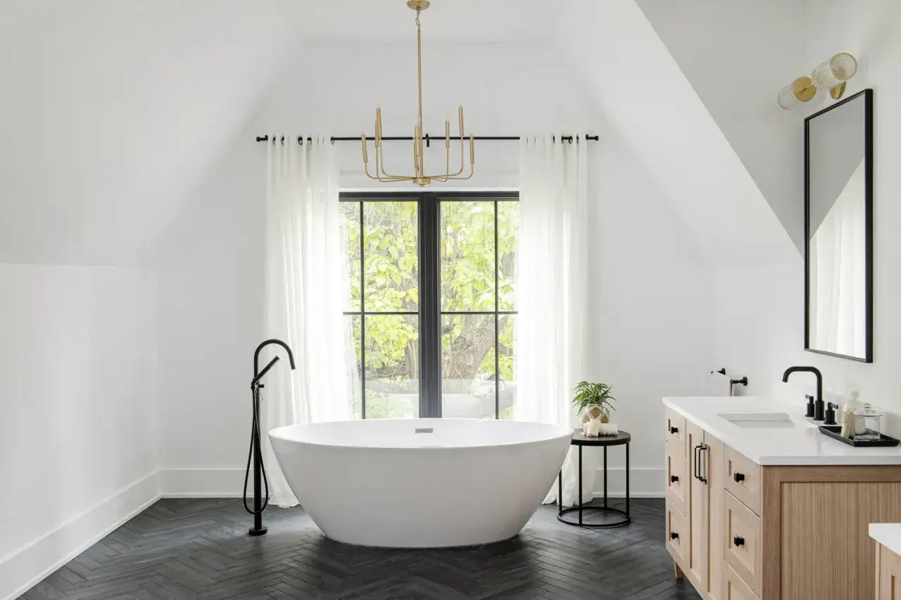 A modern bathroom with a freestanding tub and vanity, featuring striking dark floors that add depth to the bright space.