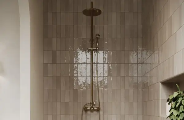 A modern shower with matte porcelain tiles and a brass showerhead. Learn how to clean matte porcelain tiles in shower spaces for a sparkling finish.