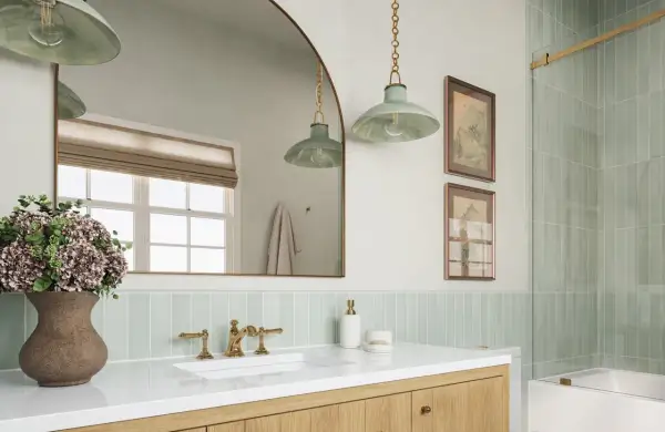 A modern bathroom with a light green vertical tile backsplash placement behind a white sink and vanity.