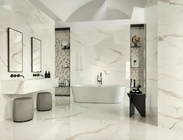 Luxurious bathroom with marble-look tiles featuring thin grout lines vs thick. A freestanding tub, double vanity, and modern stools create a spa-like atmosphere.