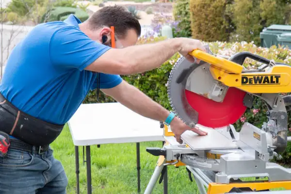 Man using a miter saw to cut SmartCore flooring. He's wearing safety glasses and ear protection.