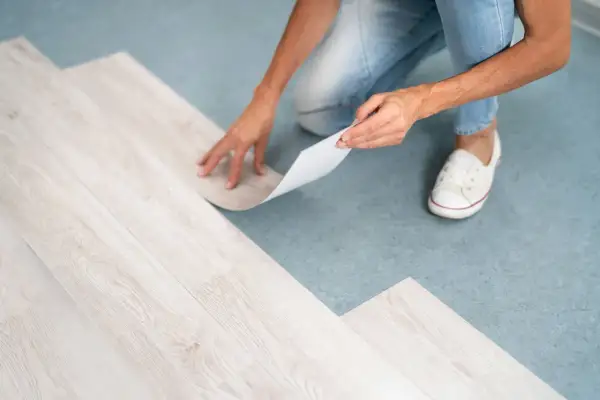 A person is installing vinyl plank flooring, but one plank isn't laying flat.