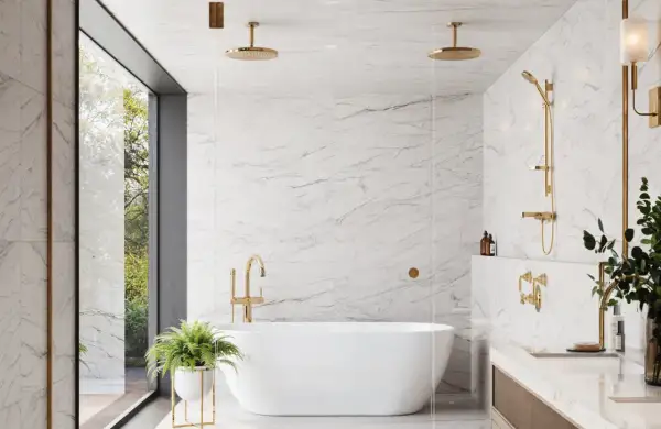 A luxurious bathroom featuring white marble tile with light grey grout, a freestanding tub, and gold fixtures.