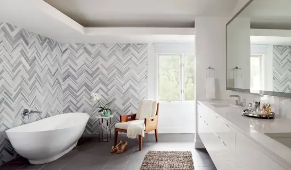 A luxurious bathroom features a freestanding tub and a stunning herringbone pattern shower wall.