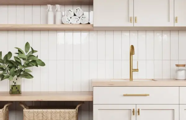 A modern laundry room with white subway tiles and subtle grout options. A gold faucet and brass hardware add a touch of luxury.