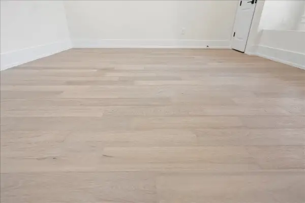 Light wood vinyl plank flooring laid in a room. This image shows the result of how to start vinyl plank flooring, with clean lines and a modern look.
