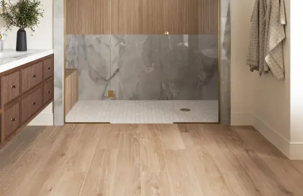 Modern bathroom with wood-look porcelain tile flooring. The shower features marble-look tile and wood accents. Considering porcelain wood tile pros and cons for your next renovation?