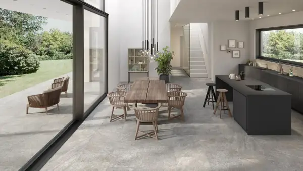 Modern dining and kitchen area with a seamless stone flooring installation, connecting indoor and outdoor spaces.