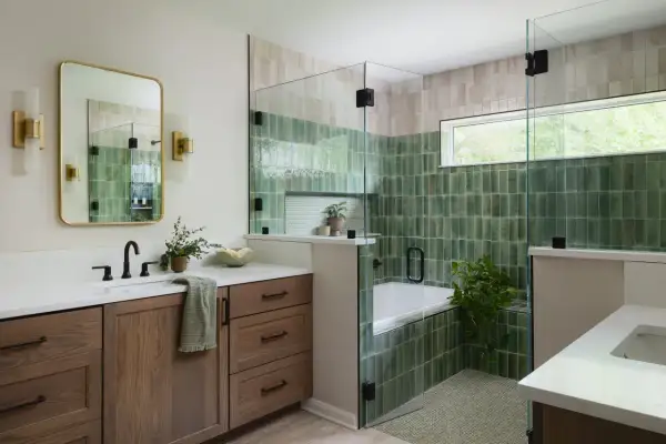 A modern bathroom features a soaking tub surrounded by glossy green and beige modern bathroom tiles, a glass shower enclosure, and a wooden vanity.