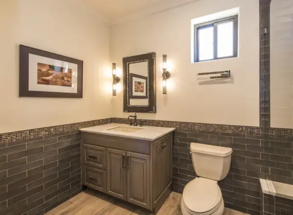 Bathroom vanity with a sink, mirror, and two wall sconces. The sconce height from floor is about 4 feet, illuminating the artwork and vanity.