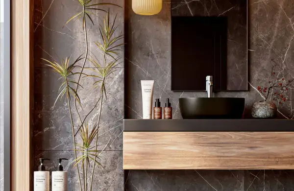 Modern bathroom vanity ideas featuring a floating wood shelf, dark vessel sink, and marble walls. A tall plant adds a natural touch.