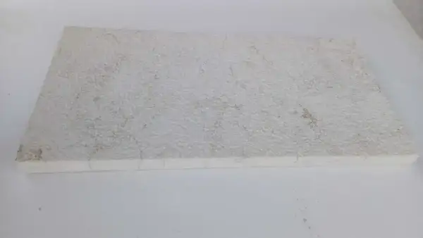 A textured, off-white limestone slab, showing some discoloration. This image could illustrate how to clean limestone.