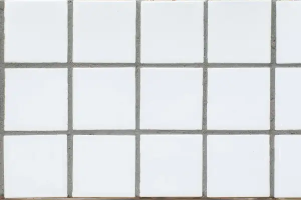 A grid of small, white square tiles with gray grout filling the spaces between them. This grout is what holds the tiles together and prevents water from seeping through.