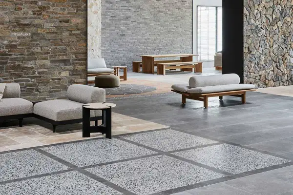 Modern living space with stone walls, wooden furniture, and a striking terrazzo design floor.