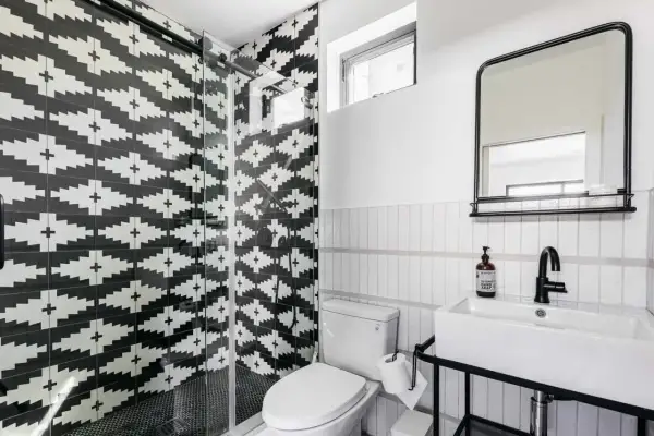 A modern bathroom with a striking black and white tile texture on the shower walls. The geometric pattern creates a bold statement.
